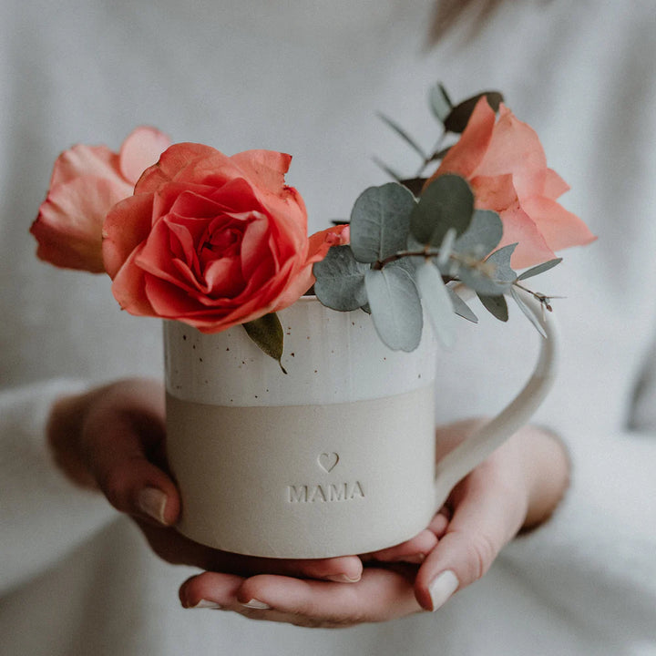 Handgefertigte grosse Tasse Mama in Cremeweiss von Eulenschnitt auf Händen mit Blume
