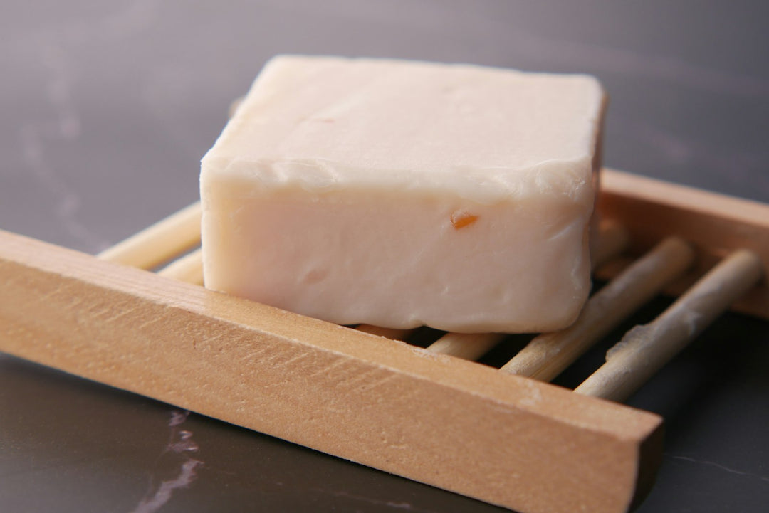 Ein Stück feste Seife liegt auf zwei Holzstäbchen zum Trocknen