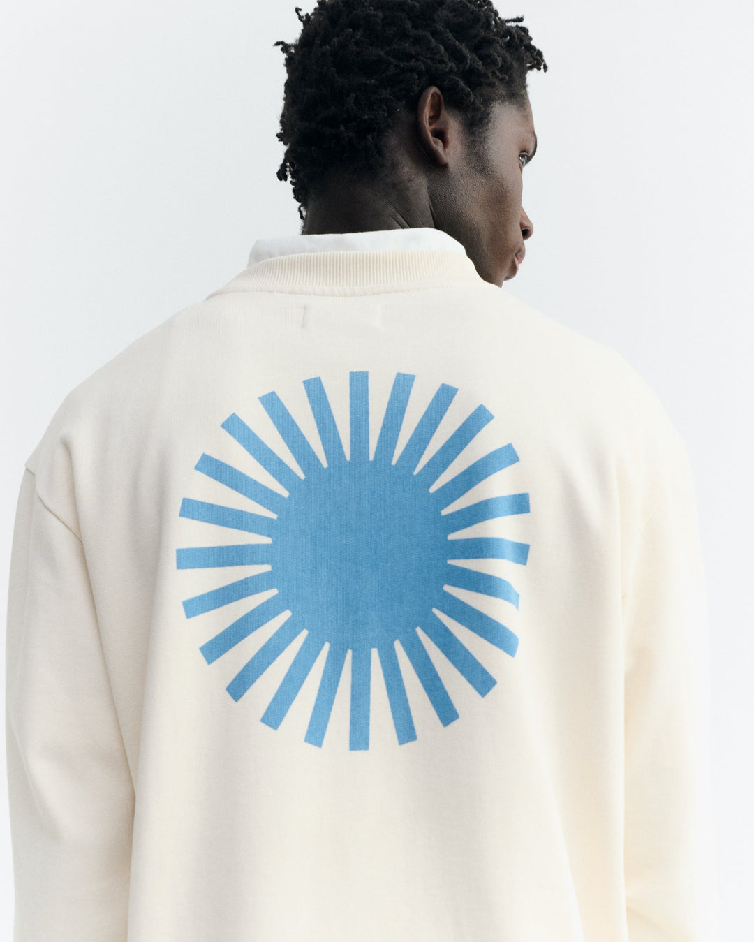 Sweatshirt Leon Ecru von Thinking MU, Nahaufnahme blaue Sonne auf dem Rücken am Model